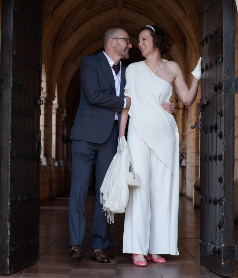 Ancient Spanish Monastery Wedding A couple in formal attire, smiling and embracing at an ornate entrance.