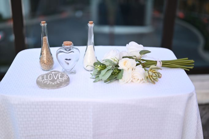 A table set with decorative bottles, a heart-shaped container, and a bouquet of white flowers.